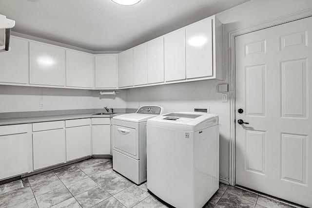 laundry area featuring sink, washer and dryer, and cabinets