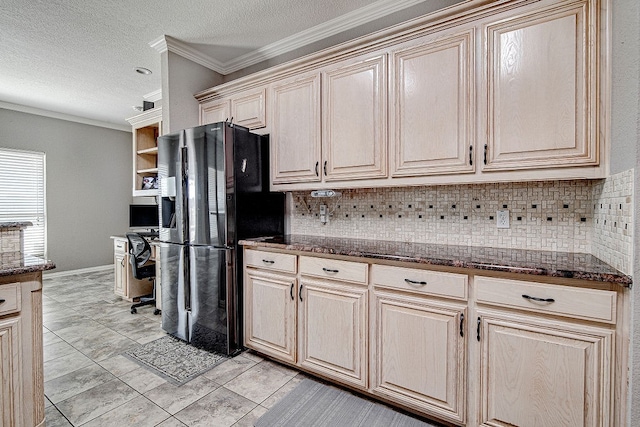 kitchen featuring black refrigerator with ice dispenser, decorative backsplash, dark stone counters, and ornamental molding