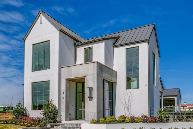 view of front facade with stucco siding, metal roof, and a standing seam roof