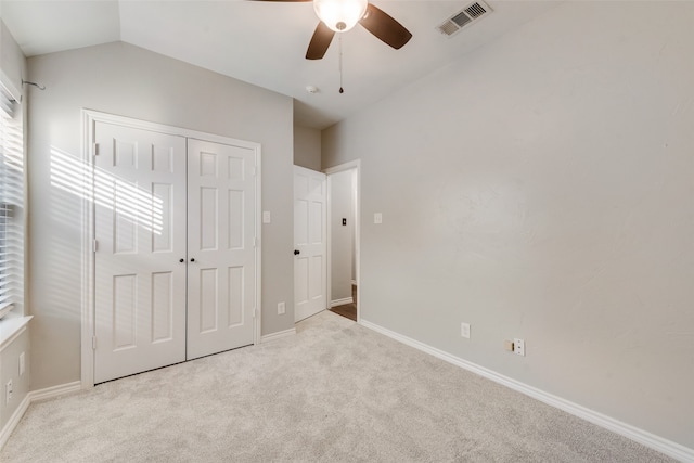 unfurnished bedroom with light colored carpet, lofted ceiling, ceiling fan, and a closet