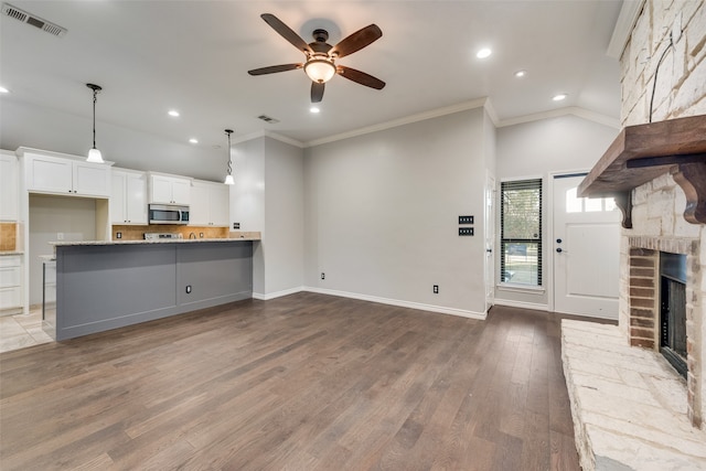 unfurnished living room with a large fireplace, ceiling fan, crown molding, and light hardwood / wood-style flooring