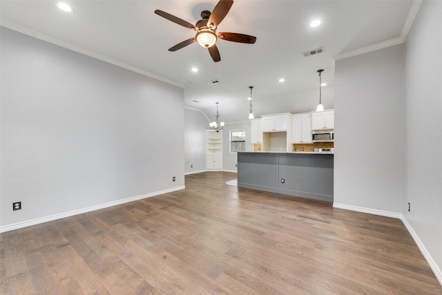 unfurnished living room featuring wood-type flooring, ceiling fan with notable chandelier, and ornamental molding