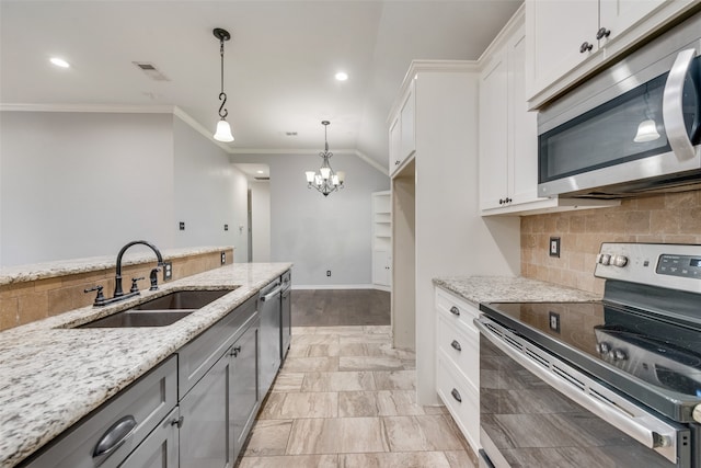 kitchen with light stone counters, appliances with stainless steel finishes, hanging light fixtures, sink, and white cabinets