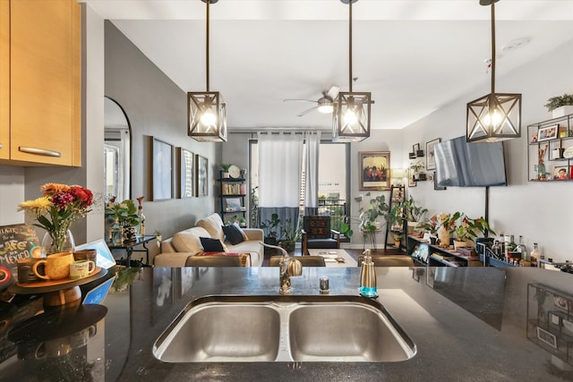 kitchen with light brown cabinetry, sink, hanging light fixtures, and ceiling fan