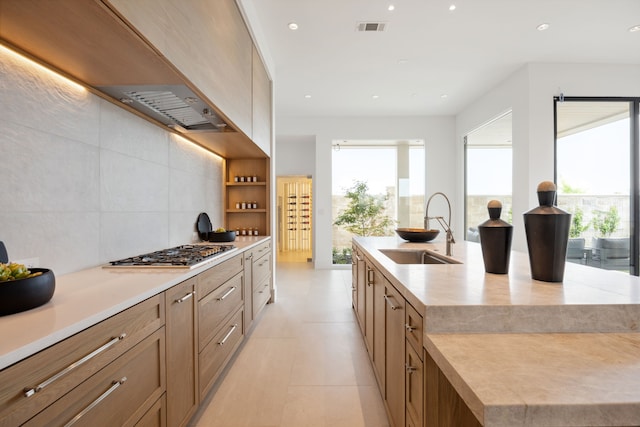 kitchen with a wealth of natural light, a sink, stainless steel gas stovetop, and light countertops