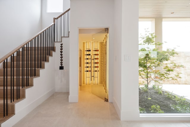 stairway with plenty of natural light, baseboards, and tile patterned flooring