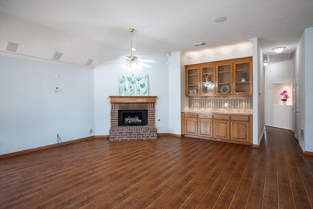 unfurnished living room with ornamental molding, ceiling fan, a fireplace, and dark hardwood / wood-style flooring