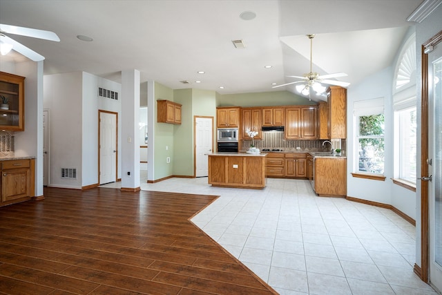 kitchen featuring ceiling fan, tasteful backsplash, stainless steel microwave, and light hardwood / wood-style floors