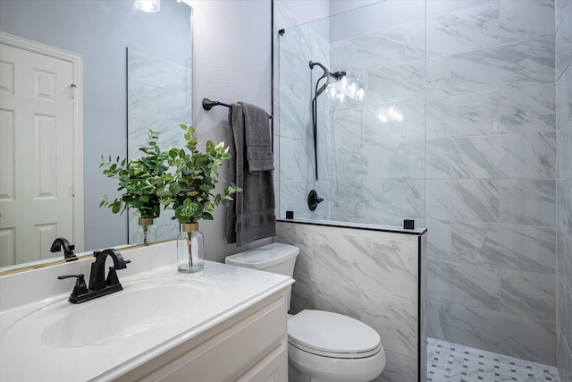 bathroom with vanity, toilet, tile walls, and tiled shower