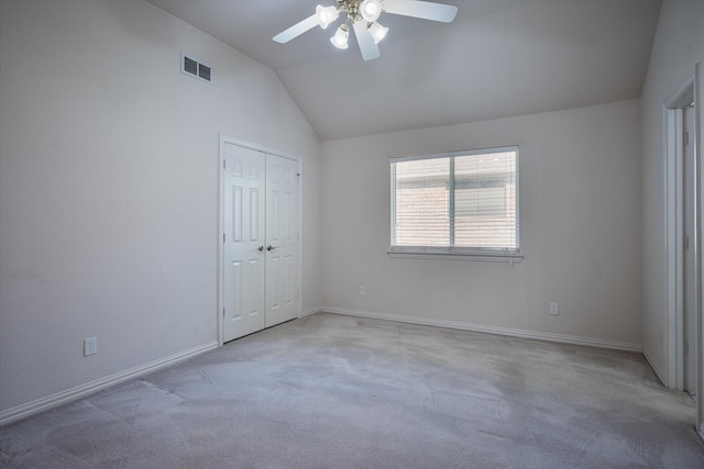 unfurnished bedroom with lofted ceiling, a closet, light colored carpet, and ceiling fan