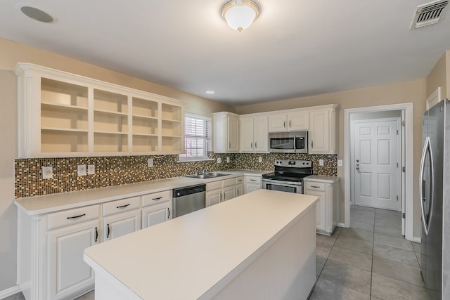 kitchen with backsplash, stainless steel appliances, a kitchen island, and white cabinets