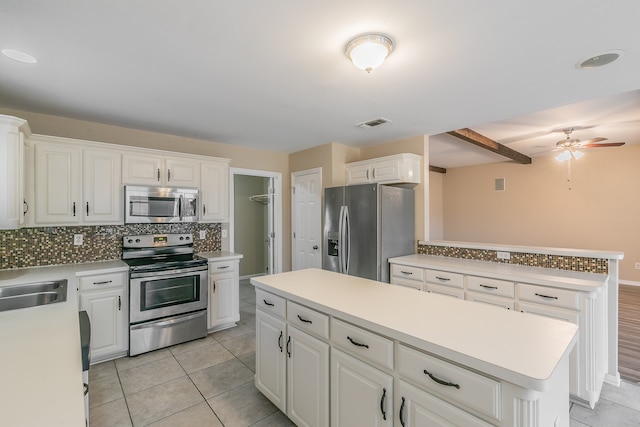 kitchen with a center island, tasteful backsplash, white cabinetry, appliances with stainless steel finishes, and ceiling fan