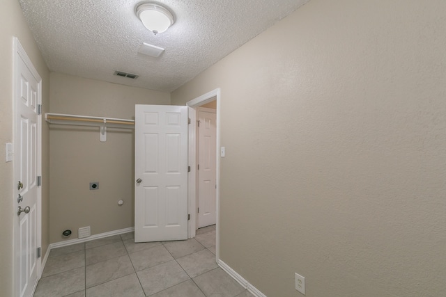 washroom featuring light tile patterned flooring, electric dryer hookup, and a textured ceiling