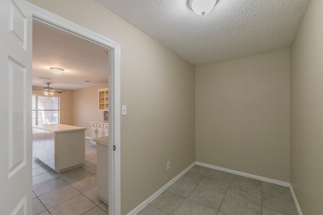 tiled empty room with a textured ceiling and ceiling fan