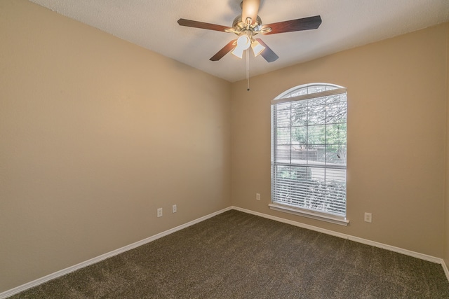 unfurnished room featuring ceiling fan and dark carpet