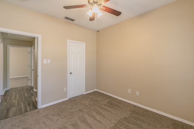 unfurnished bedroom featuring dark colored carpet, a closet, and ceiling fan