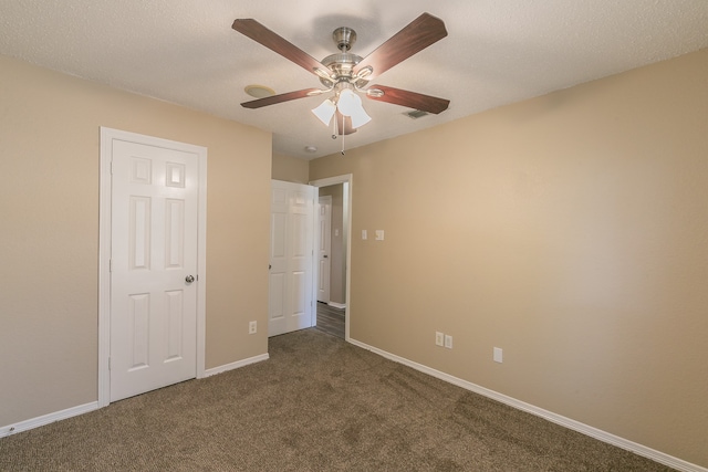 unfurnished bedroom featuring dark carpet, a textured ceiling, and ceiling fan