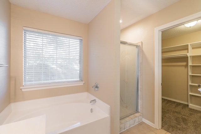 bathroom with a textured ceiling, independent shower and bath, and tile patterned flooring