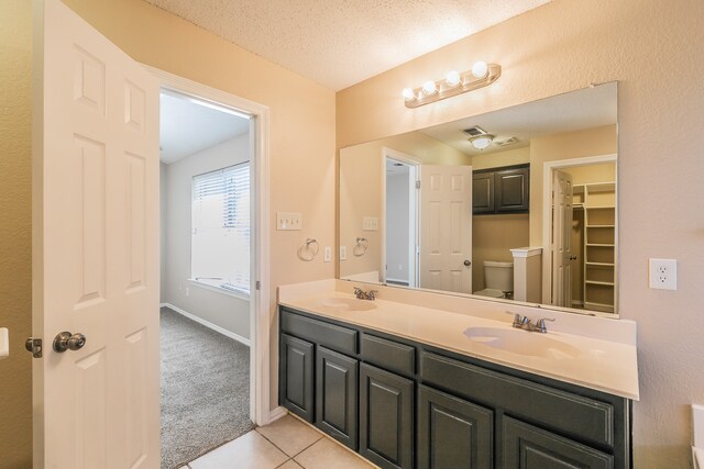 bathroom with vanity, a textured ceiling, toilet, and tile patterned floors