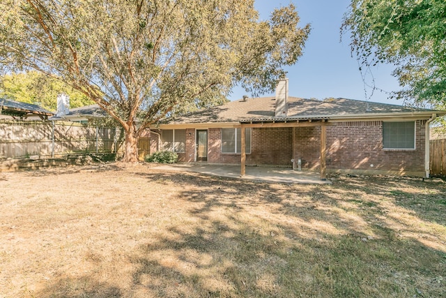 rear view of house featuring a patio and a yard