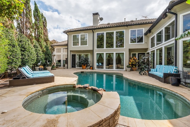 back of property with a swimming pool with hot tub and a patio