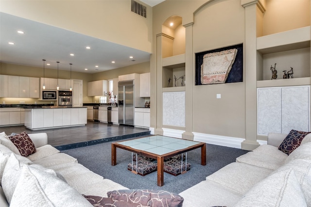 living room featuring decorative columns, built in features, and dark tile patterned flooring