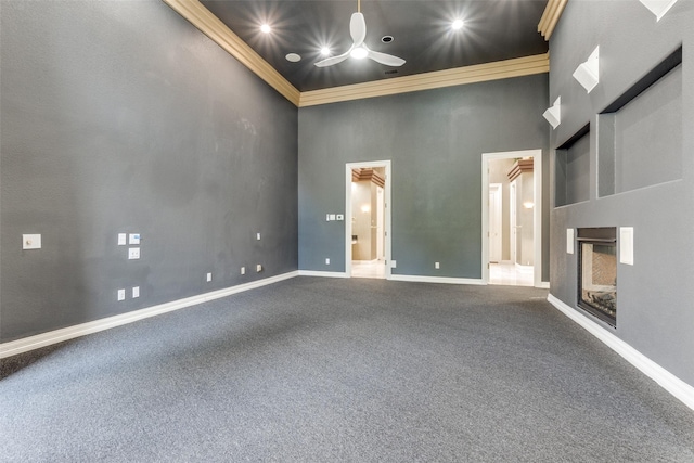 empty room with ceiling fan, crown molding, and a high ceiling