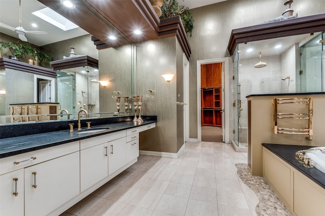 bathroom with vanity, a skylight, tile patterned flooring, ceiling fan, and walk in shower