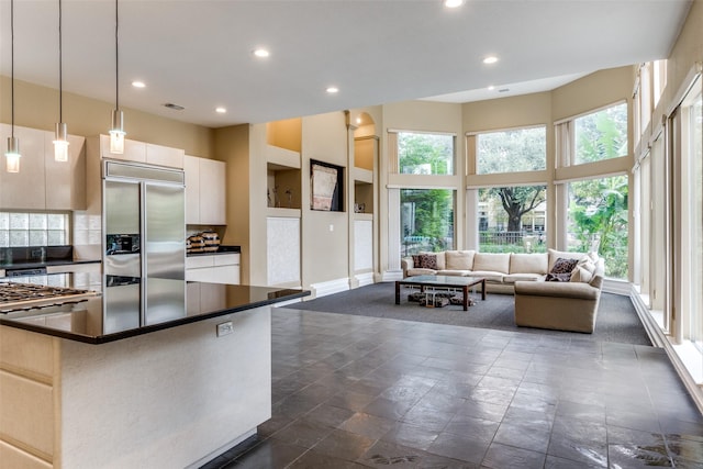 kitchen featuring decorative light fixtures, white cabinets, a high ceiling, a center island, and built in refrigerator