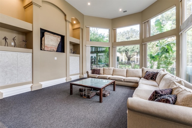 carpeted living room featuring a high ceiling, built in features, and a healthy amount of sunlight