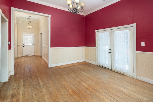 interior space with an inviting chandelier, wood-type flooring, ornamental molding, and french doors