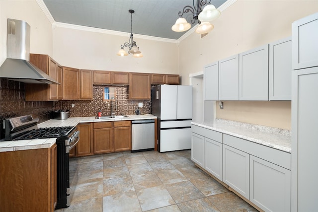 kitchen featuring appliances with stainless steel finishes, sink, hanging light fixtures, wall chimney range hood, and an inviting chandelier