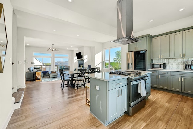 kitchen featuring island exhaust hood, a healthy amount of sunlight, appliances with stainless steel finishes, and light hardwood / wood-style floors