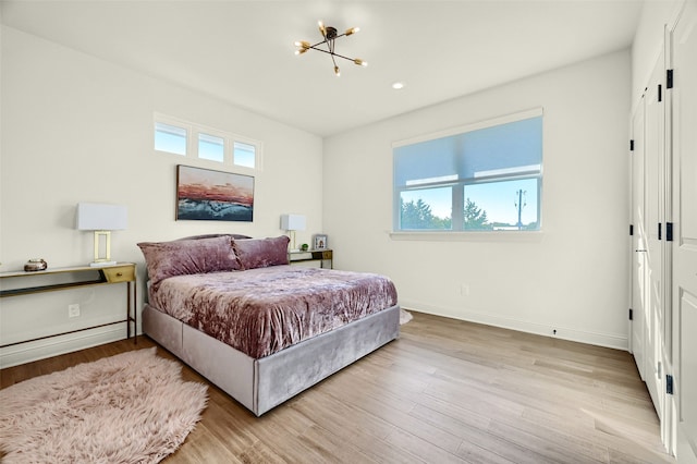 bedroom with light hardwood / wood-style flooring and a chandelier