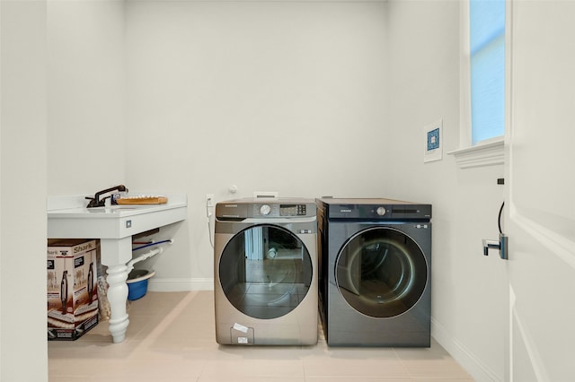 clothes washing area with independent washer and dryer and light tile patterned floors