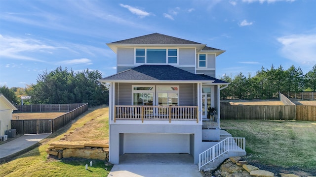 front of property featuring central air condition unit, a front yard, covered porch, and a garage