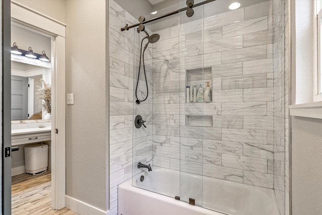 bathroom with hardwood / wood-style floors and shower / bath combination with glass door