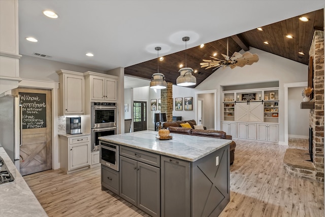 kitchen featuring light hardwood / wood-style floors, vaulted ceiling with beams, light stone counters, and gray cabinetry