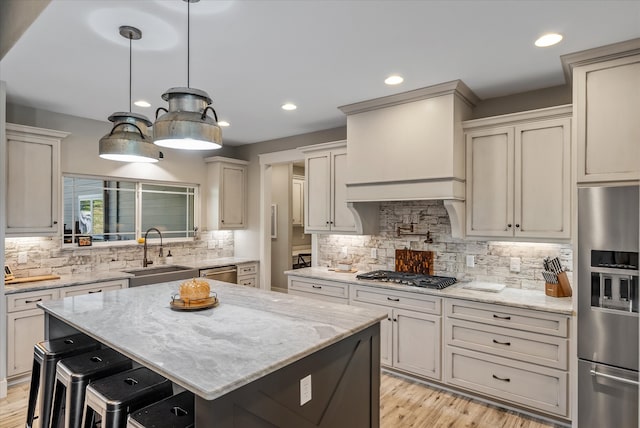 kitchen featuring stainless steel appliances, a kitchen island, light stone countertops, decorative backsplash, and sink