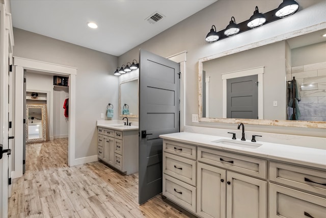 bathroom featuring wood-type flooring, vanity, and a tile shower