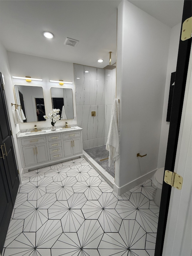 bathroom featuring a tile shower, vanity, and toilet