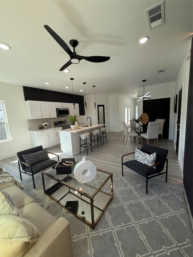 living room with ceiling fan, wood-type flooring, and sink