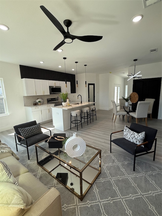 living room featuring ceiling fan, sink, and hardwood / wood-style floors