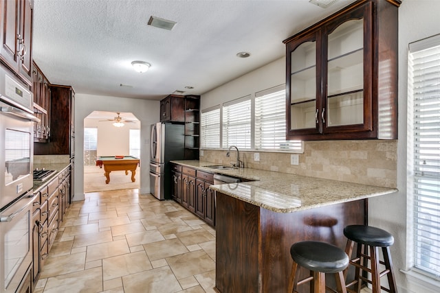 kitchen featuring appliances with stainless steel finishes, sink, a kitchen breakfast bar, billiards, and kitchen peninsula