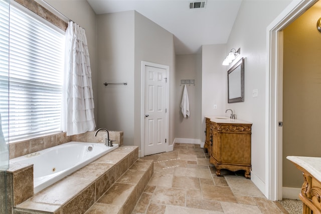 bathroom with vanity and tiled tub