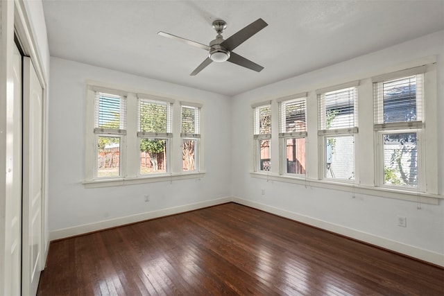 empty room featuring ceiling fan, plenty of natural light, and dark hardwood / wood-style flooring