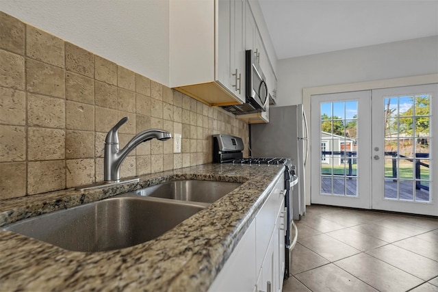 kitchen with tasteful backsplash, french doors, white cabinetry, stainless steel appliances, and dark stone counters