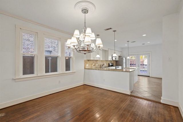 kitchen featuring kitchen peninsula, hanging light fixtures, dark hardwood / wood-style flooring, appliances with stainless steel finishes, and white cabinetry