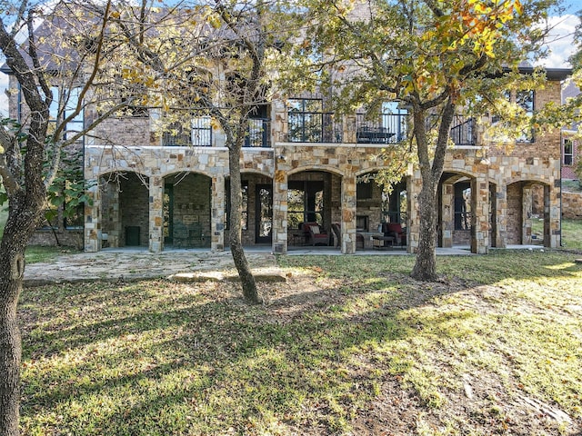 view of front facade with a patio, a front yard, and a balcony