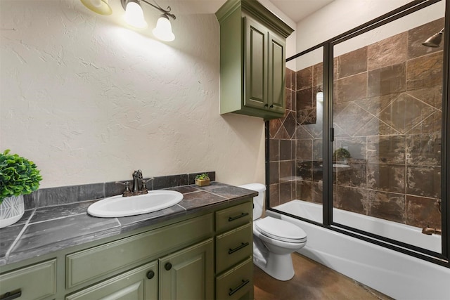 bathroom featuring toilet, shower / bath combination with glass door, vanity, and a textured wall